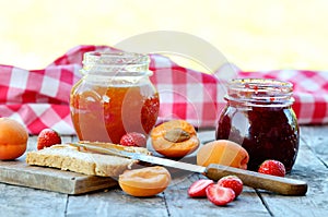 Jar of apricot and strawberry jam, fresh apricots and strawberries