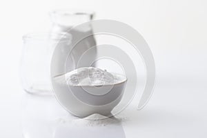 Jar with artificial sweetener aspartame E951 and a bowl on a white glossy background