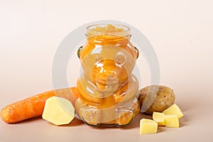 Jar of baby puree with carrot and spoon isolated on white