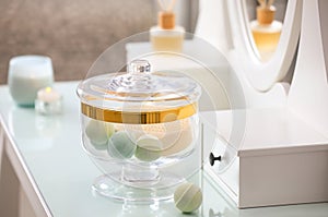 Jar with bath bombs and bath sponge on dressing table