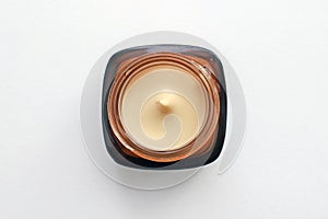 Jar with beige cosmetic cream.