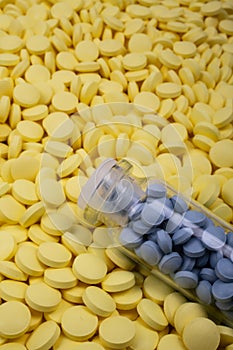 Jar of blue pills lies on yellow medicines. Drugs, painkillers, colds macro
