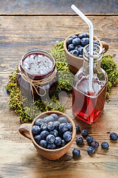 Jar of blueberry jam, bottle of juice and bowls of blueberries