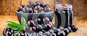 Jar of Brazilian fruit jam, called jabuticaba or jaboticaba, on a rustic wooden table photo