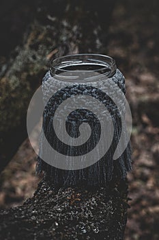 Jar with a burning candle decorated with knitted macrame