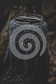 Jar with a burning candle decorated with knitted macrame