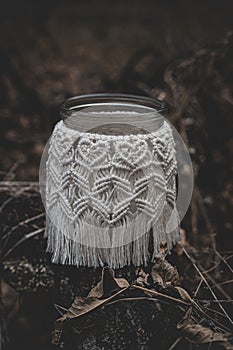 Jar with a burning candle decorated with knitted macrame