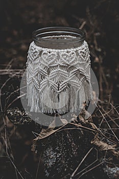 Jar with a burning candle decorated with knitted macrame