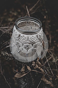 Jar with a burning candle decorated with knitted macrame