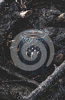 Jar with a burning candle decorated with knitted macrame