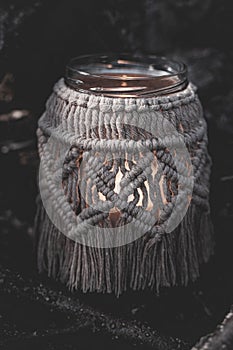 Jar with a burning candle decorated with knitted macrame