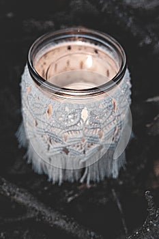 Jar with a burning candle decorated with knitted macrame