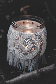 Jar with a burning candle decorated with knitted macrame