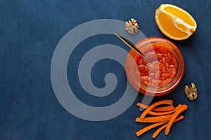 A jar of carrot jam on a dark background with a copy space
