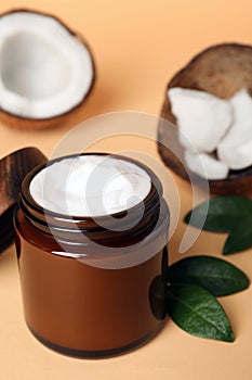 Jar of coconut face cream on light orange background