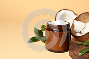 Jar of coconut face cream on light orange background. Space for text
