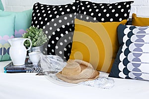 Jar, coffee cup and books with colorful pillows in background