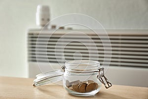 Jar with coins near calorifer at home. Heating saving concept