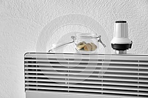 Jar with coins and thermostat on calorifer at home. Heating saving concept