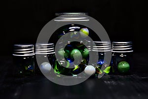 Jar with colored marbles on a black surface