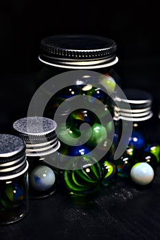 Jar with colored marbles on a black surface