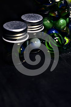 Jar with colored marbles on a black surface