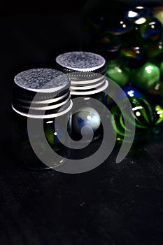 Jar with colored marbles on a black surface photo