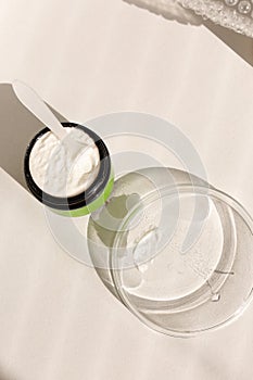 Jar of cosmetic clay powder with spoon and plate with water.