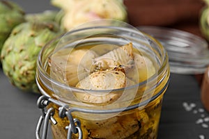 Jar of delicious artichokes pickled in olive oil on table, closeup