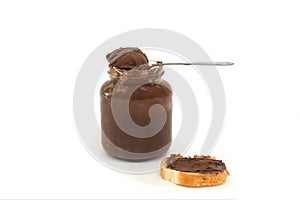 Jar with delicious chocolate cream spread with a slice of baguette and a spoon isolated on white background