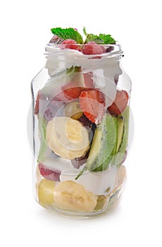 Jar with delicious fruit salad and cream on white background