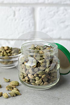 Jar with dry cardamom pods on light table