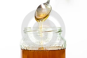 Jar filled with delicious honey, puring honey from the spoon