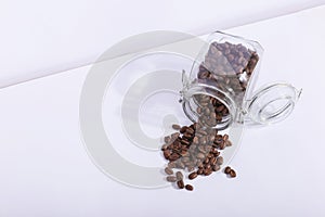 A jar of fresh fragrant coffee beans, on a white background. Hard shadow from the sun, art concept of morning and energy charge