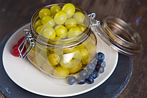 Jar of fresh grapes, blueberries and raspberries on white plate and slate plate in overhead view