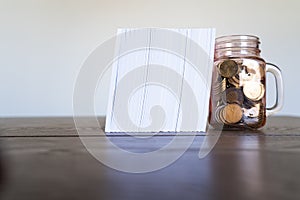 A jar full of coins used as a bookend for a stack of Notebooks