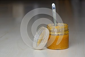 A jar of ghee or clarified butter with a steel spoon on a wooden textured background. photo