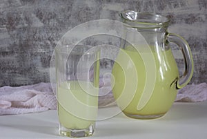 Jar and glass with liquid whey that remains after formation of curds on white background