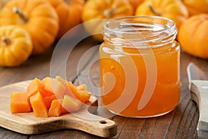 Jar of healthy pumpkin jam. Chopped pumpkin pulp on a cutting board.