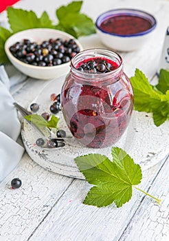 Jar of homemade fresh currant jam with shugar. Fresh berries black currant on white wooden background