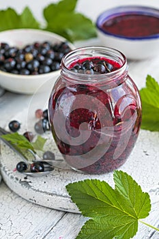 Jar of homemade fresh currant jam with shugar. Fresh berries black currant on white wooden background