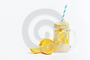 A jar of homemade lemonade and lemons on a white background