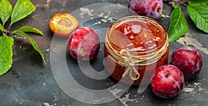 Jar with homemade plum jam on a wooden background. banner, menu, recipe place for text