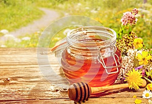 Jar of honey with dipper with flowers