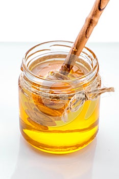 Jar of honey with honey dipper inside on white background