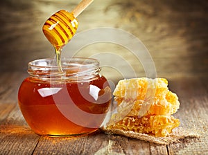 Tarro de miel con panal de abeja en la mesa de madera.
