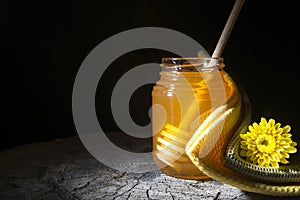 Jar of honey and stick to honey on a wooden background