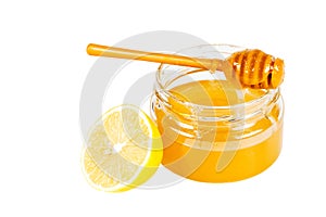 Jar of honey with a wooden drizzler and a lemon.