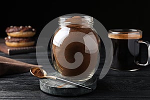 Jar of instant coffee and spoon on black wooden table
