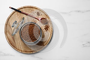 Jar of instant coffee and spoon on white marble table, top view. Space for text